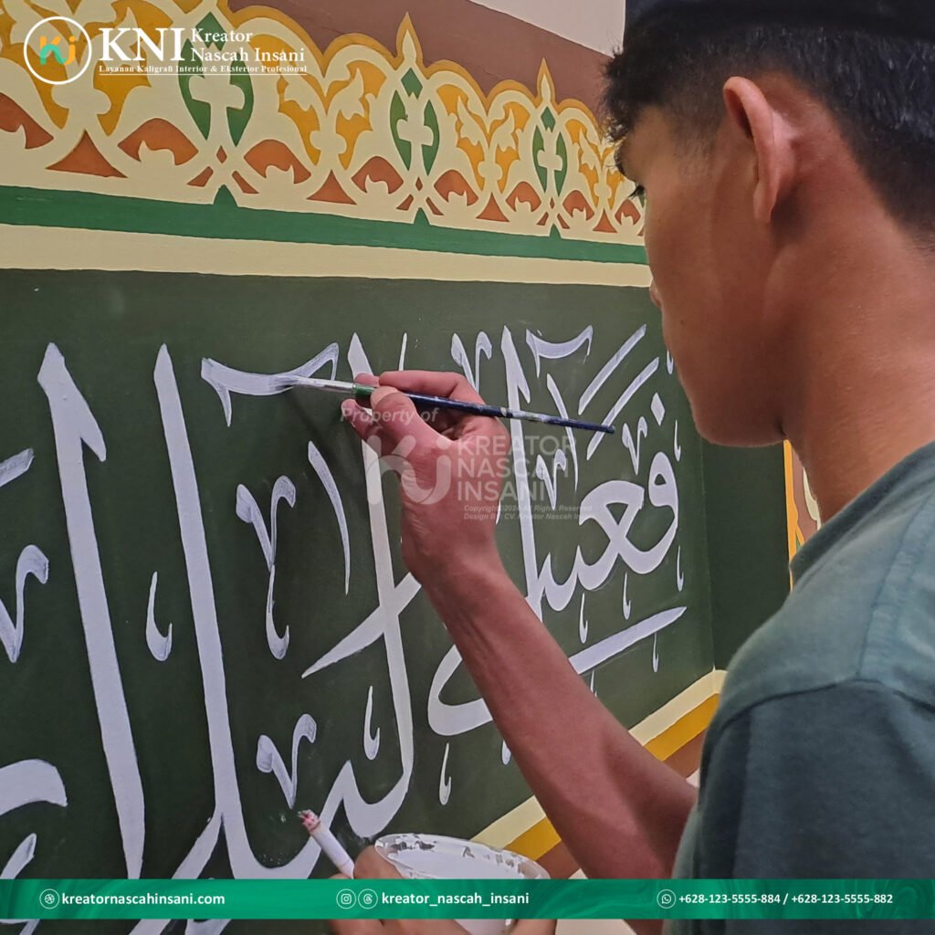 Seorang kaligrafer sedang menulis khat Tsuluts dengan pena khusus di atas kertas, menunjukkan detail dan keahlian seni kaligrafi.